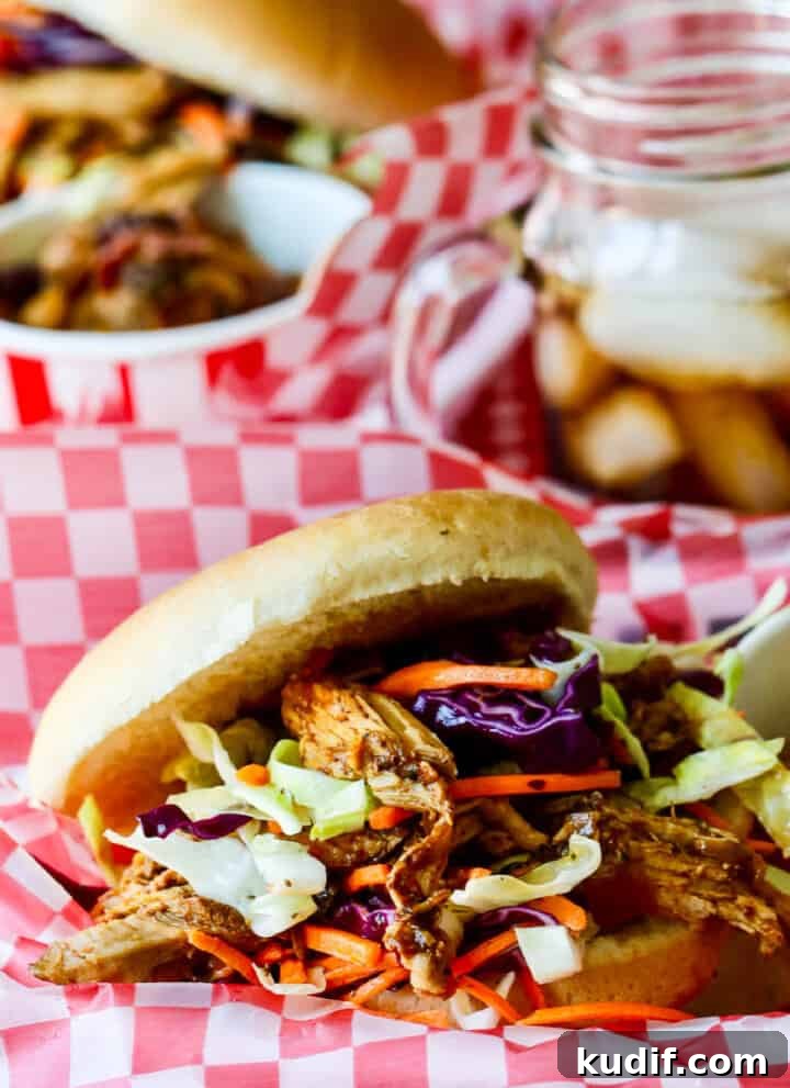 Red white check paper lined basked holding a pulled pork sandwich topped with coleslaw.