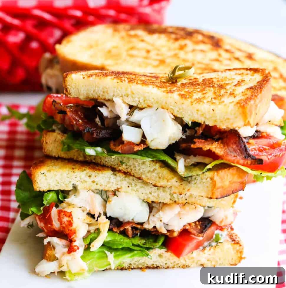 Lobster BLT Sandwich with Crispy Bacon and Lemon Aioli 20 A sliced open BLT sandwich loaded with succulent lobster, bacon, lettuce and tomato stacked on a board.