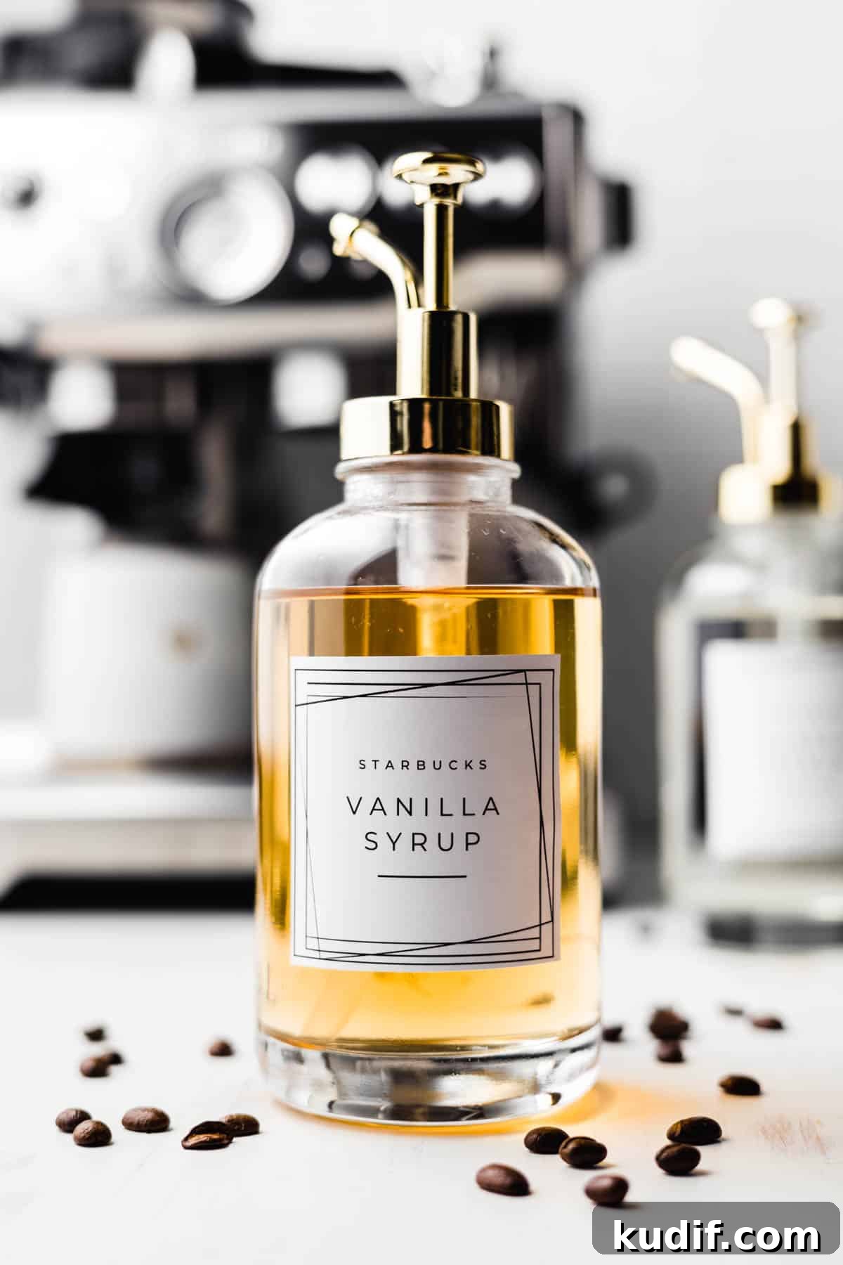 Starbucks vanilla syrup in a glass pump jar surrounded by coffee beans.