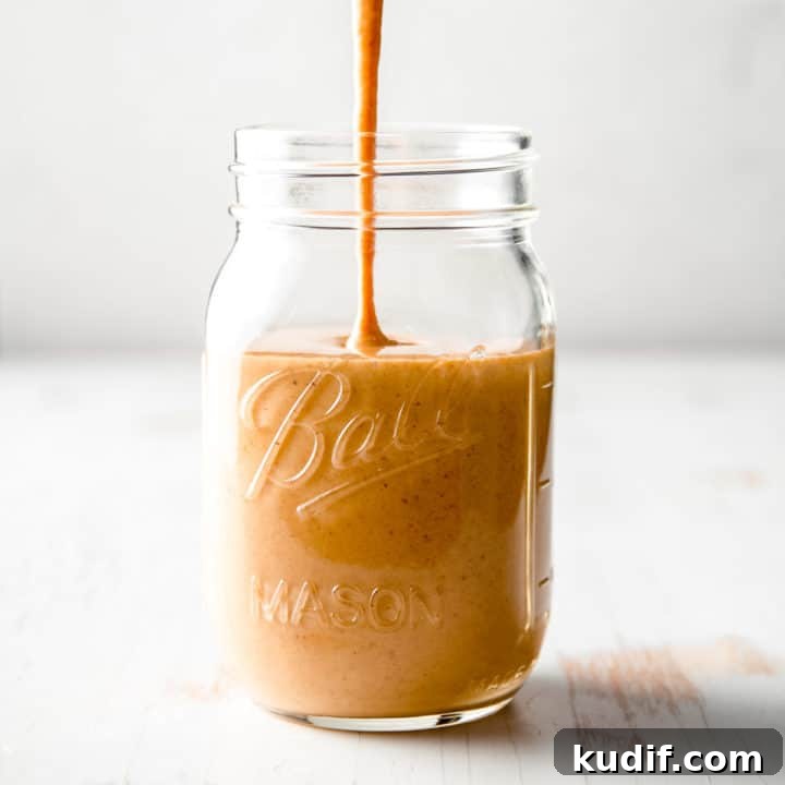 A stream of copycat Starbucks pumpkin spice sauce pouring into a mason jar.