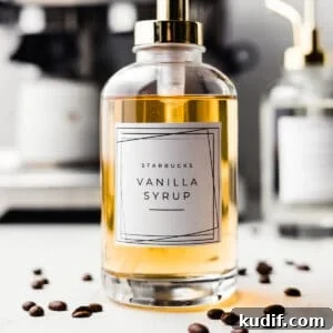 Starbucks vanilla syrup in a glass pump jar surrounded by coffee beans.