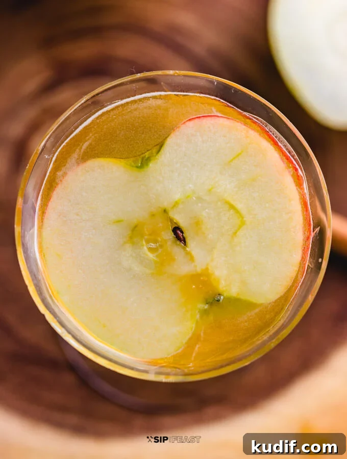 Apple Cider Cocktail - sipandfeast.com #cocktails #bourbon #drinkrecipes Overhead view of the glass with the apple cider cocktail and a slice of apple.