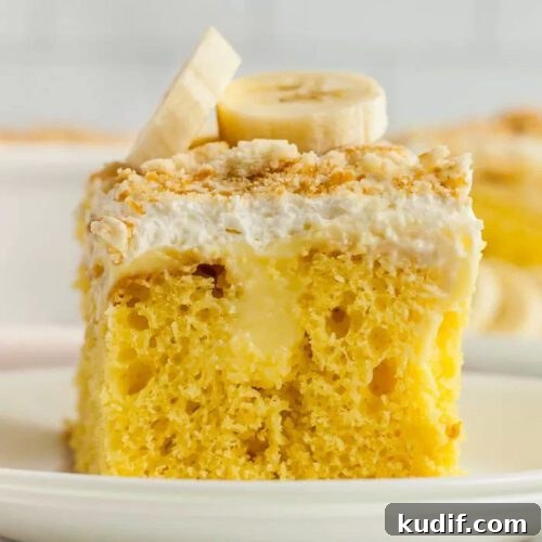 Irresistible Banana Dessert Recipes You’ll Love 3 Side view of a slice of this banana pudding poke cake on a white plate topped with crushed vanilla wafers and sliced bananas