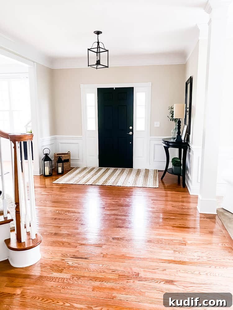 foyer view looking at front door with table and mirror on right side of photo and floor basket and lanterns on left side of photo large area rug in front of door