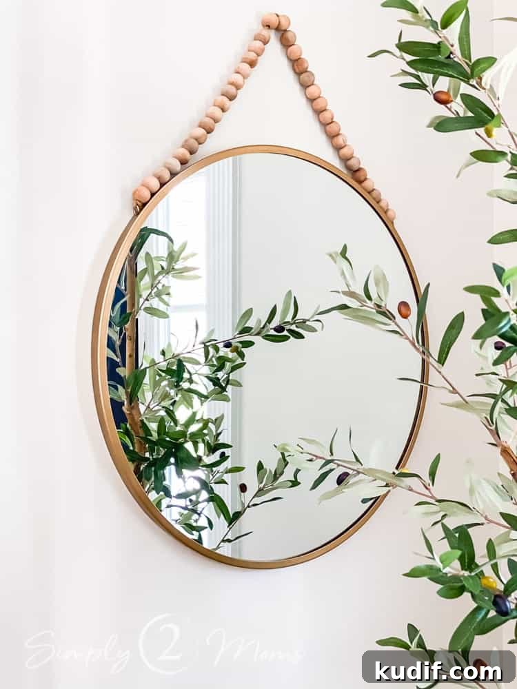 close up of metal round mirror with wood bead hanger on wall in entryway