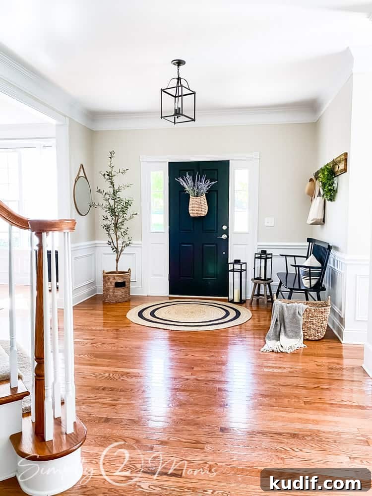 view of entryway from hallway staircase to left of photo door straight ahead with bench to right side and faux olive tree to left side of photo