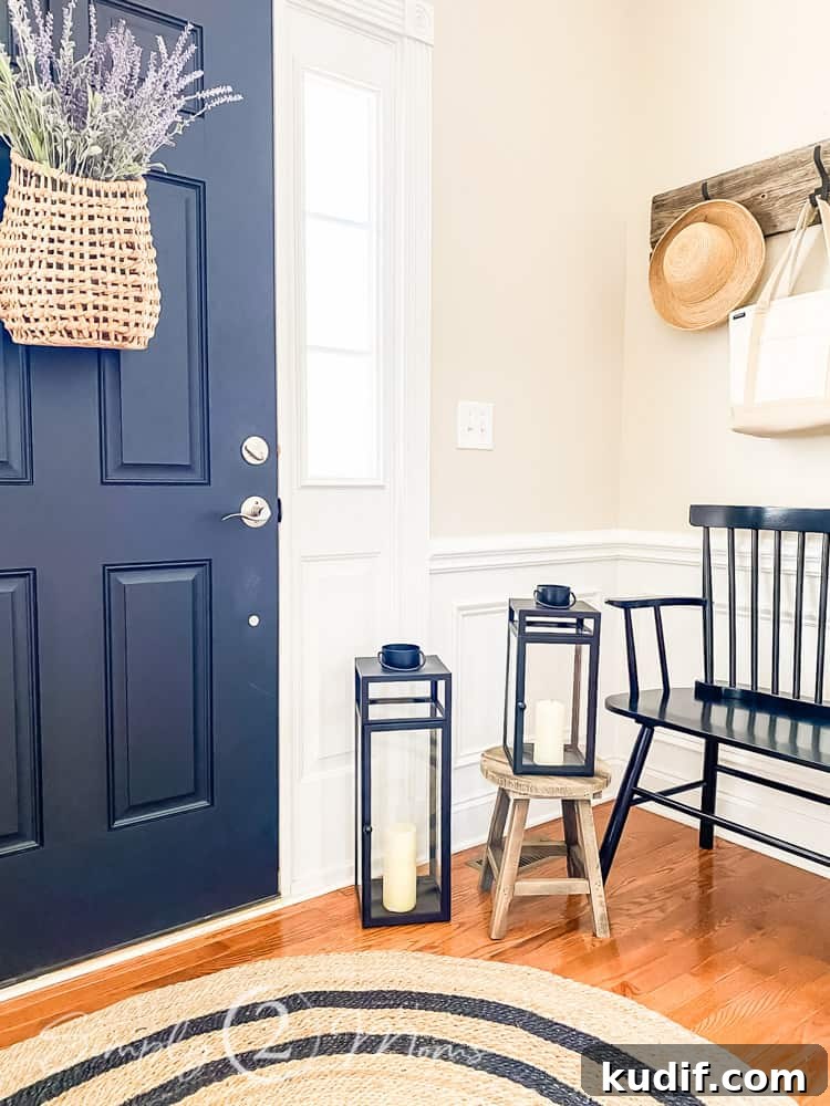close up of candle lanterns smaller one sitting on small wood stool larger one on floor beside stool front door to left of lantern and bench to right of photo