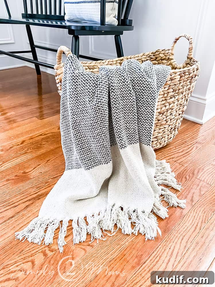 throw blanket hanging out of basket with handles on floor in front of bench