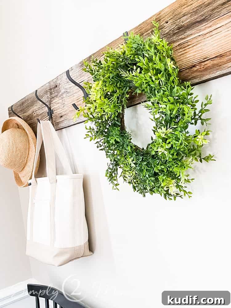 close up of faux wreath on row of hooks in front entryway