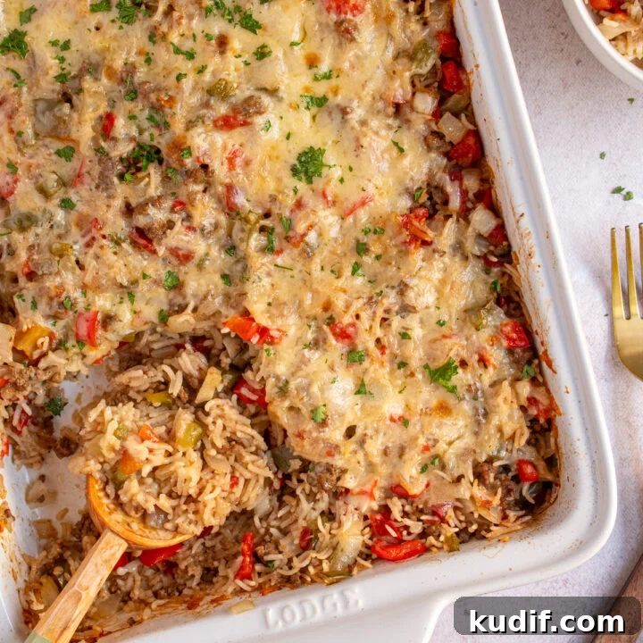A white dish with stuffed pepper casserole with a wooden spoon scooping the casserole.