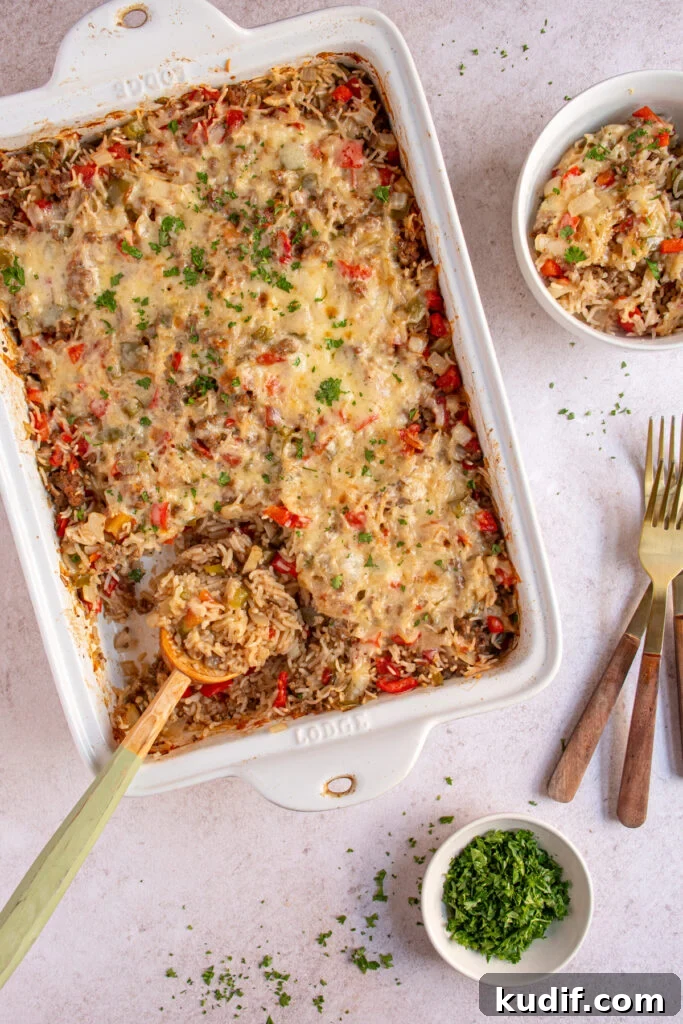 Cheesy Stuffed Pepper Casserole Bake Recipe 8 Over head view of a baking dish and bowl with stuffed pepper casserole with a wooden spoon showing the cooked rice, ground beef, and bell peppers.