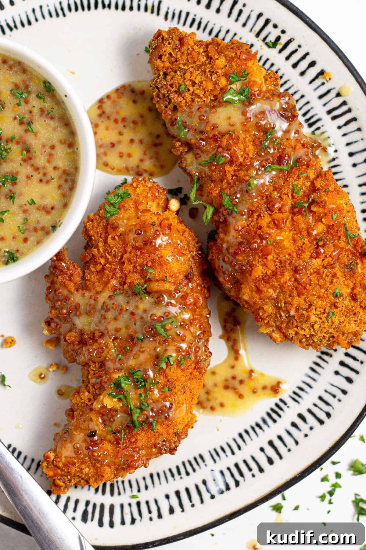Overhead shot of baked chicken tenders on a white plate garnished with fresh parsley 