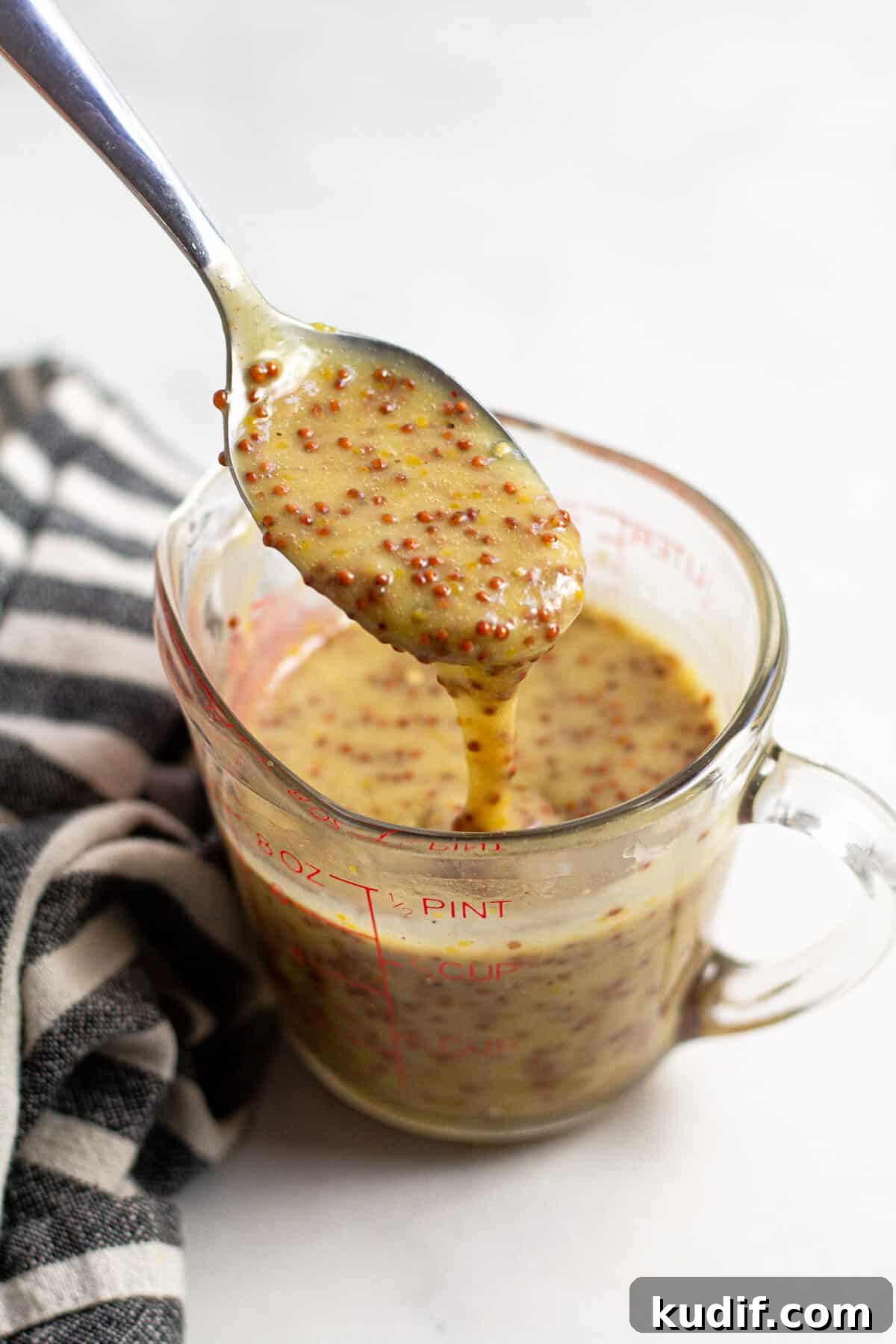 Close up shot of a spoon with honey mustard sauce dripping off of it 