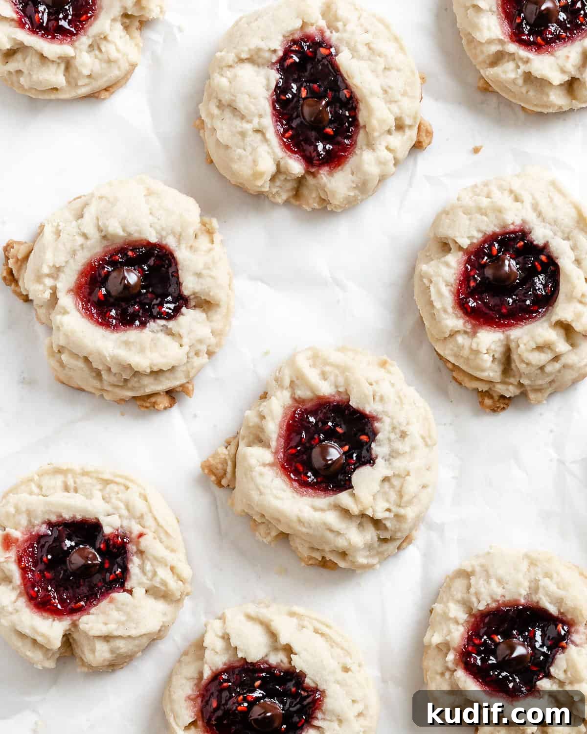 Raspberry Jam Thumbprint Cookies Recipe for Soft, Buttery Cookies 2 completed Raspberry Jam Thumbprint Cookies scattered on a white surface