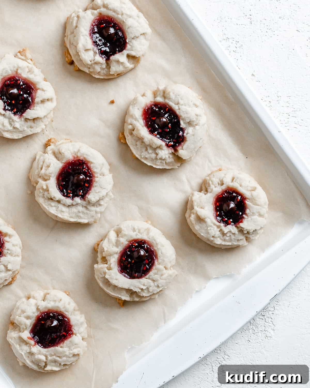 Raspberry Jam Thumbprint Cookies Recipe for Soft, Buttery Cookies 19 completed Raspberry Jam Thumbprint Cookies scattered on a baking sheet