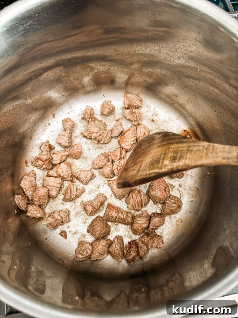 The beef pieces browning in a pan