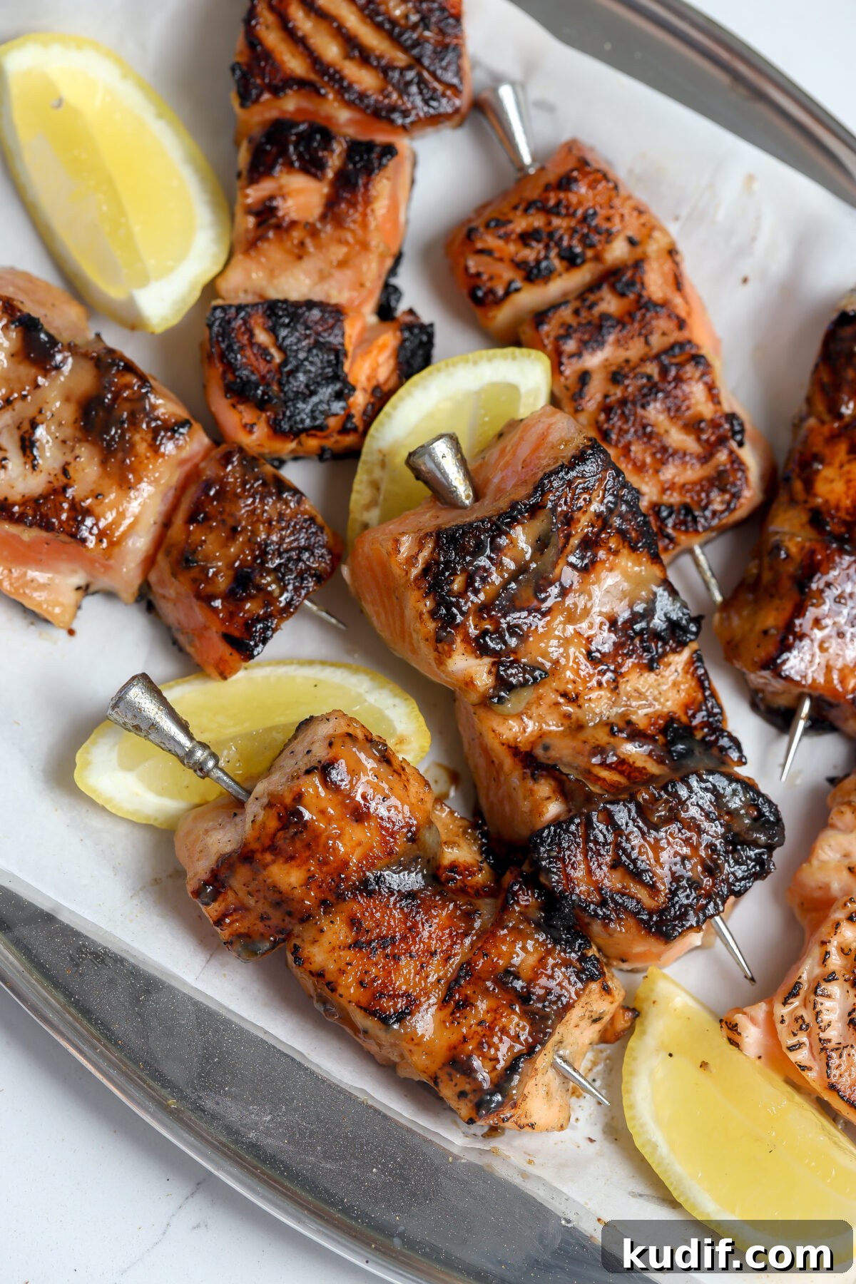 Miso-Glazed Salmon Skewers with Sesame and Scallions 2 A recipe for Miso glazed salmon skewers on a bed of rice next to sliced lemon.