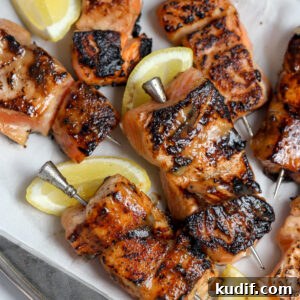 Miso-Glazed Salmon Skewers with Sesame and Scallions 9 A recipe for Miso glazed salmon skewers on a bed of rice next to sliced lemon.