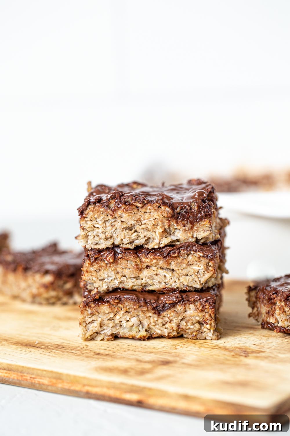 A stack of baked oatmeal bars topped with chocolate..
