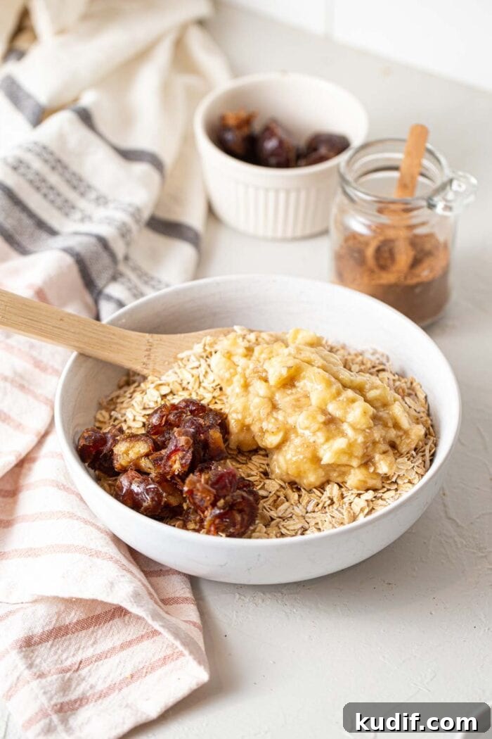 A bowl of oats topped with mashed banana and chopped dates.