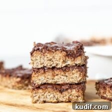 A stack of baked oatmeal bars topped with chocolate..