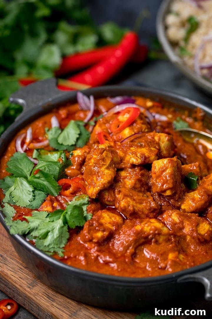 Authentic Chicken Madras Curry Recipe for Bold Flavor 2 chicken madras in a dark serving bowl on a wooden board