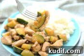 Teriyaki Garlic Chicken Stir Fry on a blue plate with rice and a fork is taking a bite