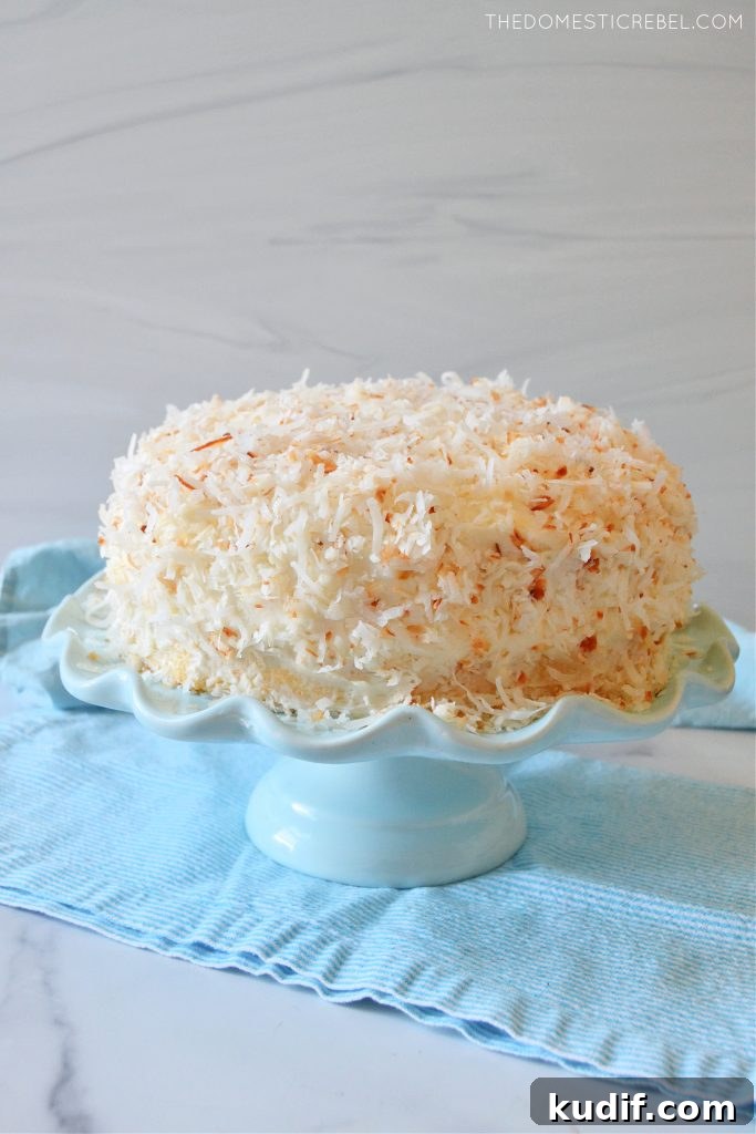 Ultimate Coconut Layer Cake Recipe for Moist, Fluffy Slices 3 coconut layer cake on a blue cake stand