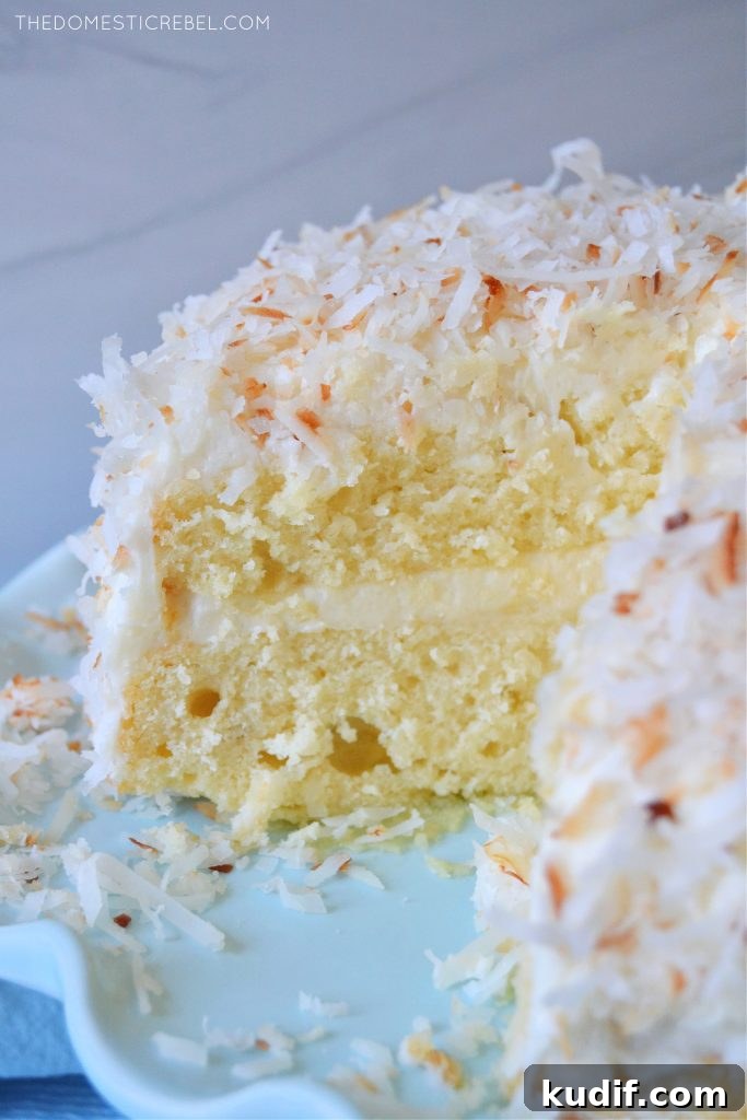 Ultimate Coconut Layer Cake Recipe for Moist, Fluffy Slices 4 coconut layer cake on a blue pedestal