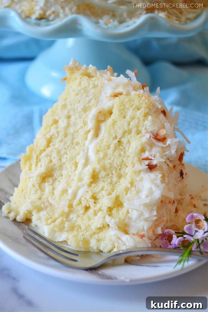 Ultimate Coconut Layer Cake Recipe for Moist, Fluffy Slices 5 coconut layer cake slice with flowers and a fork on a plate