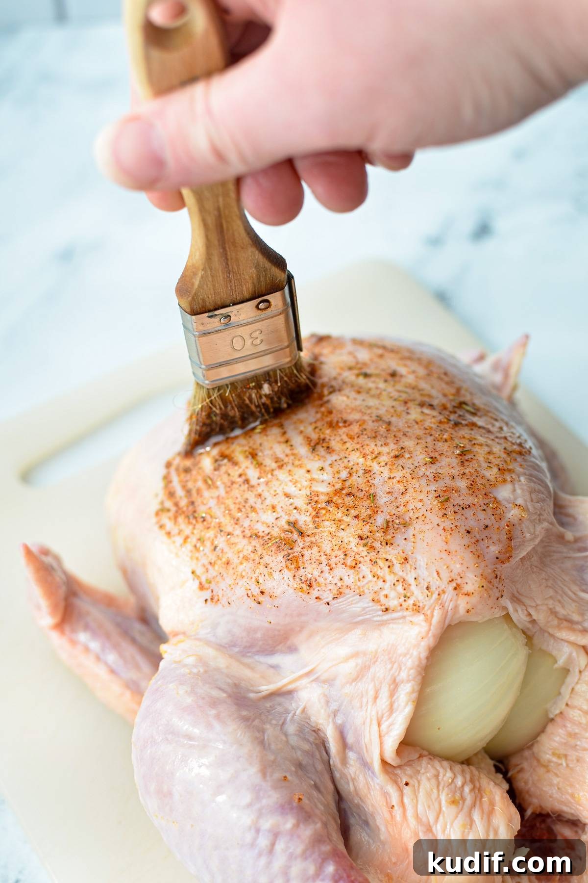 Rotisserie-Style Whole Chicken in the Air Fryer 7 Brushing a raw chicken with a seasoning blend.