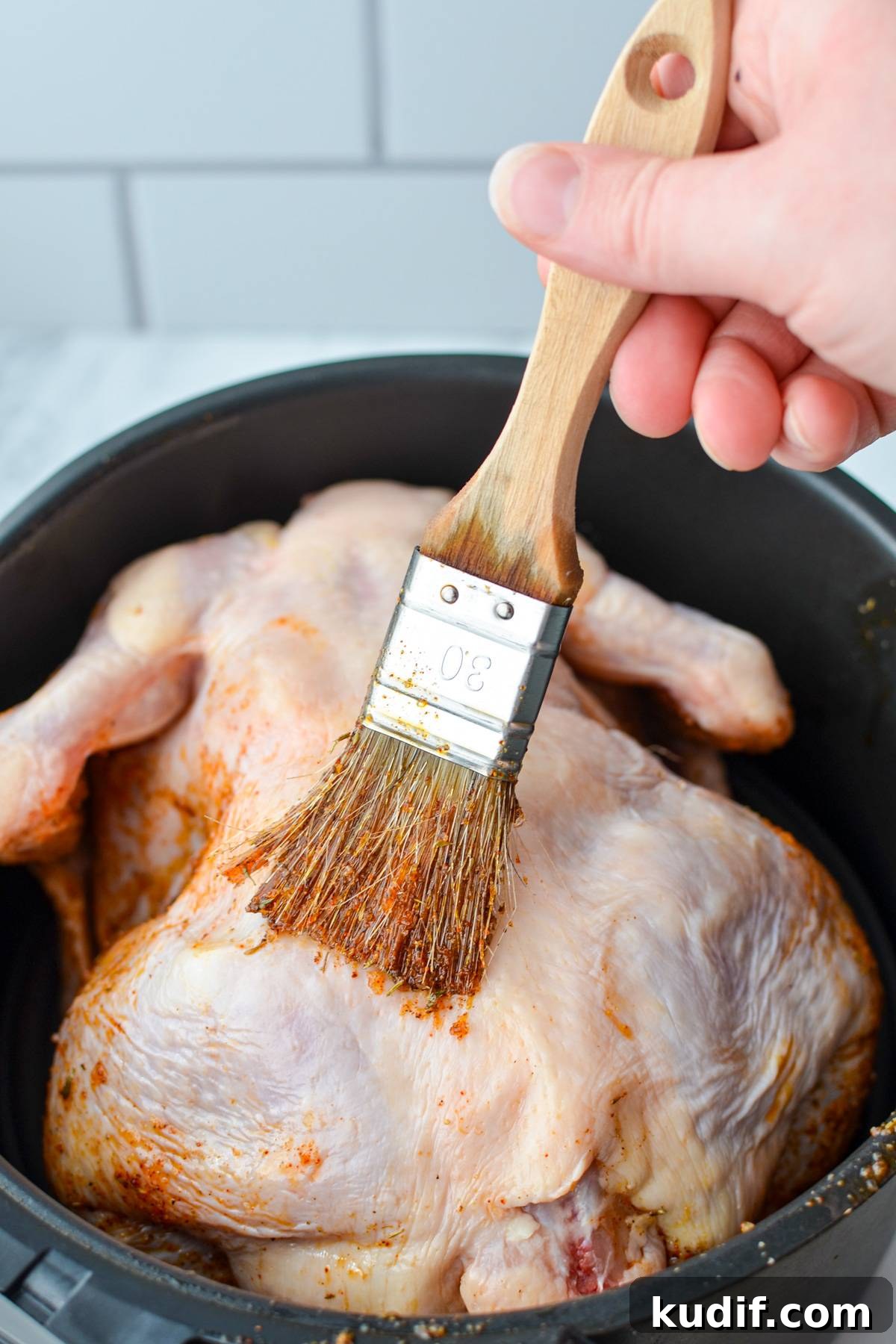 Rotisserie-Style Whole Chicken in the Air Fryer 9 Brushing a whole chicken with a spice blend with oil.