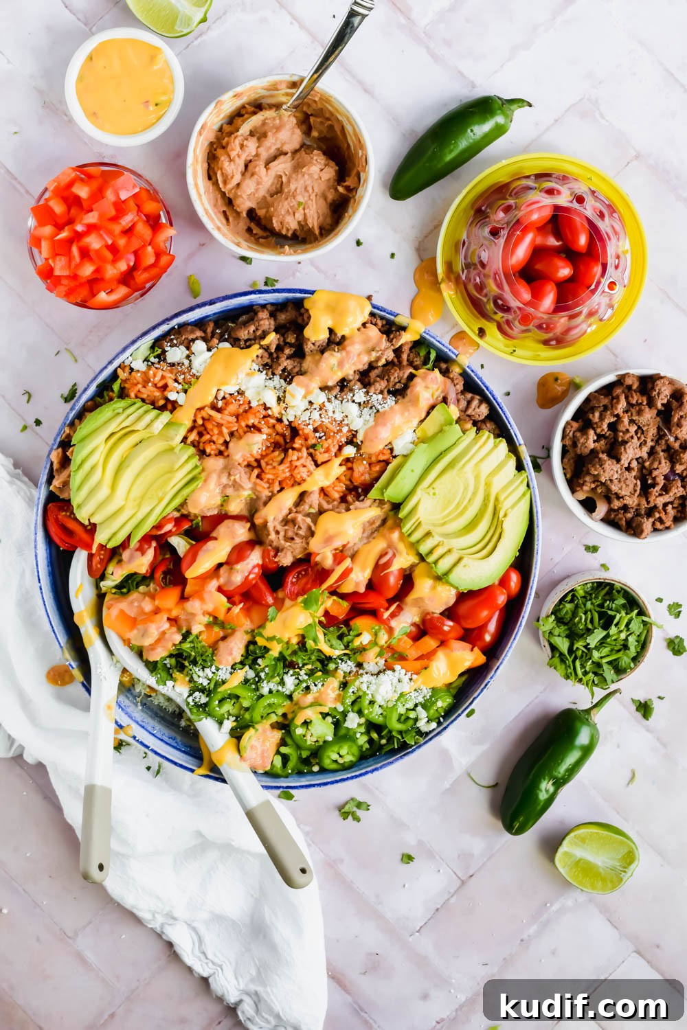 Finished healthy 7 layer salad bowl garnished with queso and avocado slices in large bowl.