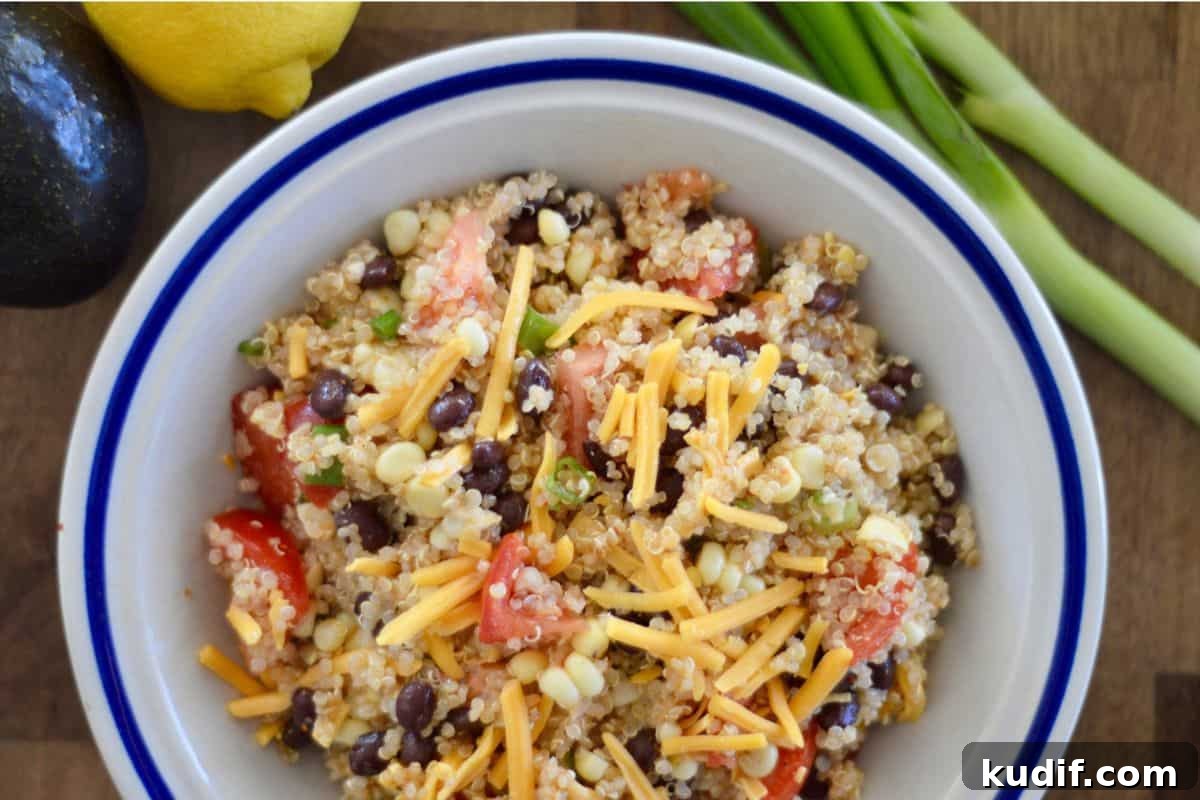 Mexican-Style Quinoa Salad with Corn, Black Beans & Lime Dressing 5 Mexican Quinoa salad with black beans, corn, and shredded cheddar cheese in a white bowl.