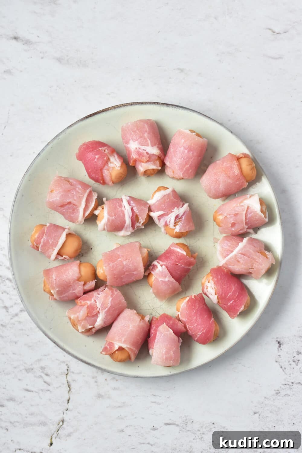 pigs in a blanket ready for oven on round plate, overhead view