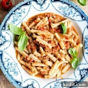 Fresh No-Cook Tomato Pasta Sauce Recipe for Quick Dinners 10 A cropped square image of pasta in tomato sauce in a blue and white vintage style bowl.