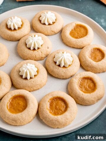 A plate of pumpkin pie filled thumbprint cookies with whipped cream.