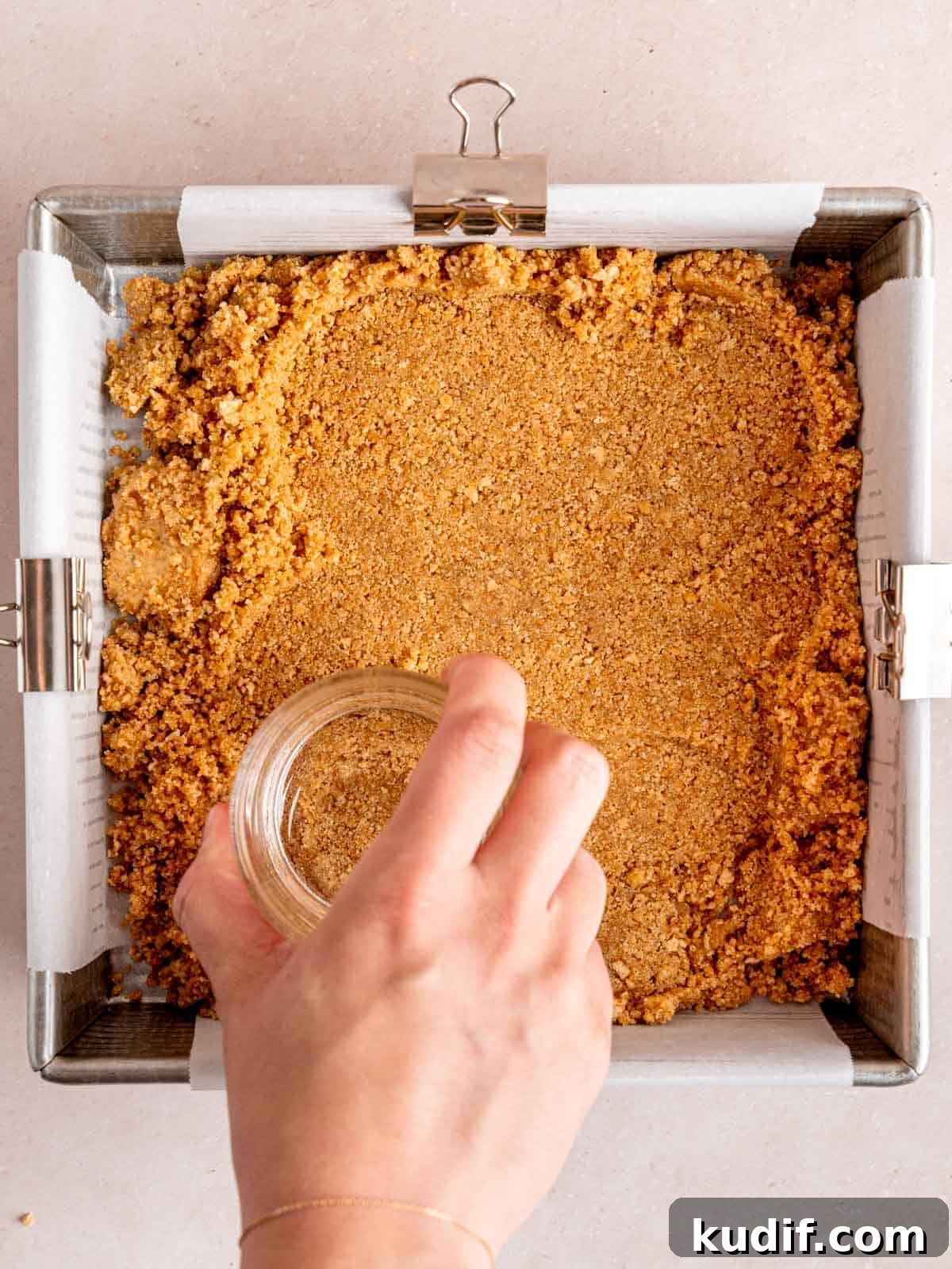 Pumpkin Cheesecake Bars Recipe for Fall Dessert Lovers 5 Pressing graham cracker crust into the bottom of an 8x8 inch pan.