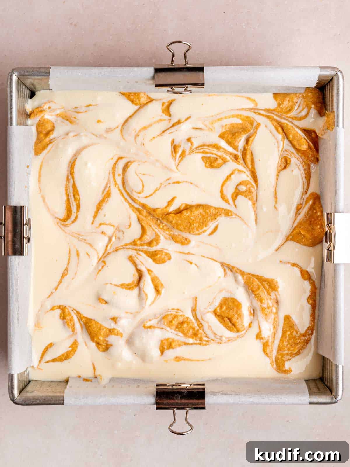 Pumpkin Cheesecake Bars Recipe for Fall Dessert Lovers 9 Vanilla and pumpkin cheesecake fillings swirled together in a square baking pan.