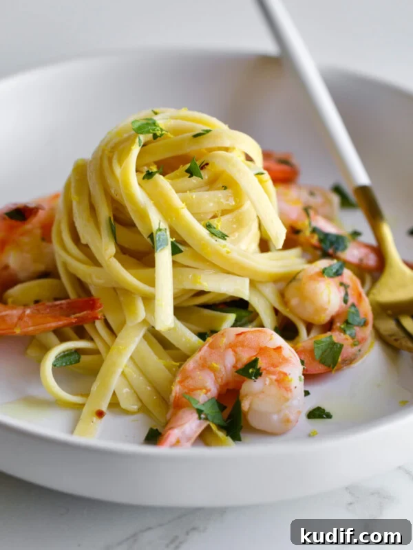 Shrimp scampi pasta on a plate with parsley and a fork.