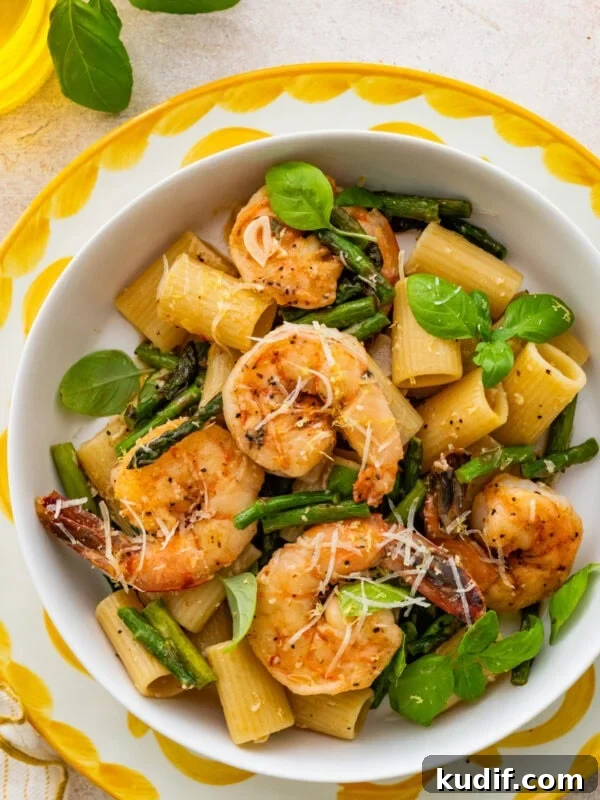 Shrimp asparagus pasta in a bowl, garnished with basil.