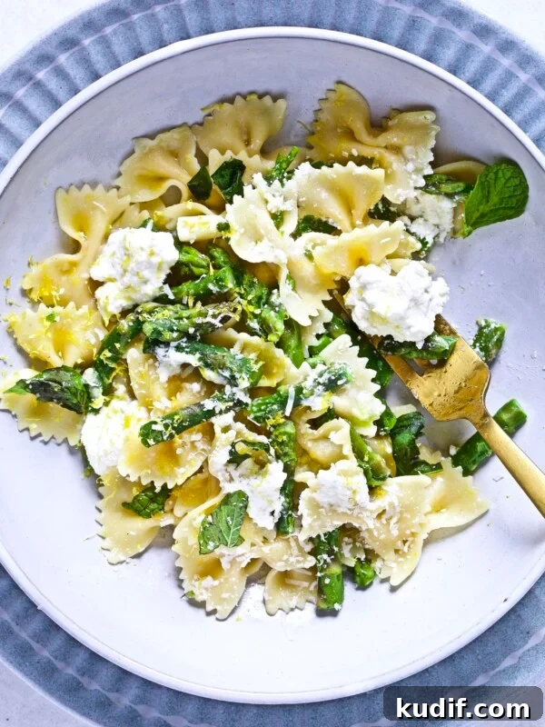 Fork grabbing lemon ricotta pasta with asparagus from a bowl.