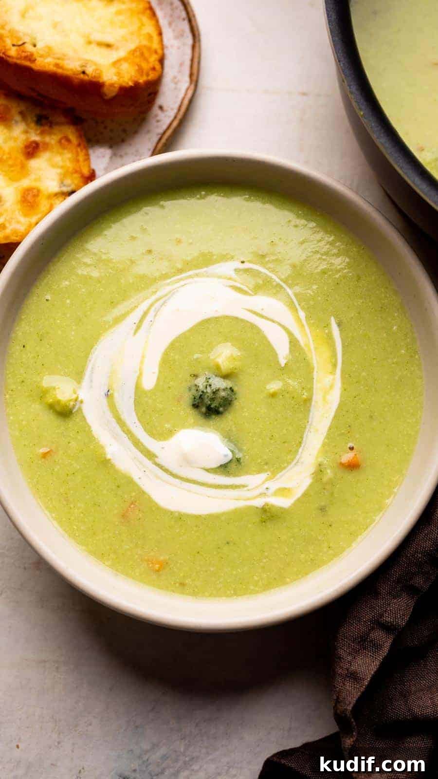 Cream-Free Broccoli Soup Recipe — Smooth, Light, and Flavorful 2 Healthy broccoli soup served in a white bowl with garlic bread on the side