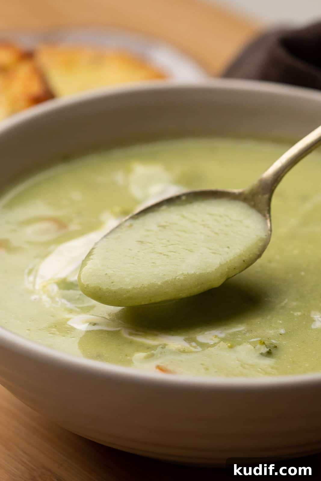 Cream-Free Broccoli Soup Recipe — Smooth, Light, and Flavorful 3 A spoon of healthy broccoli soup being taken out of the bowl