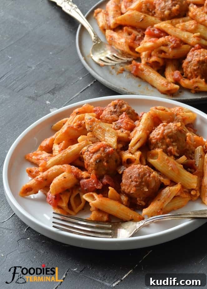 instant pot penne pasta and meatballs on a white plate with fork