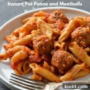 penne pasta and meatballs served on a white plate with a fork