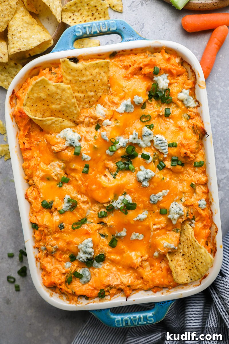 Lightened-Up Buffalo Chicken Dip Recipe for Game Day 2 A small casserole dish filled with baked healthier buffalo chicken dip topped with blue cheese crumbles and sliced green onion