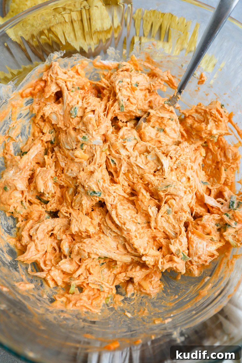 Lightened-Up Buffalo Chicken Dip Recipe for Game Day 5 A large clear mixing bowl filled with buffalo chicken dip ready to be baked in the oven