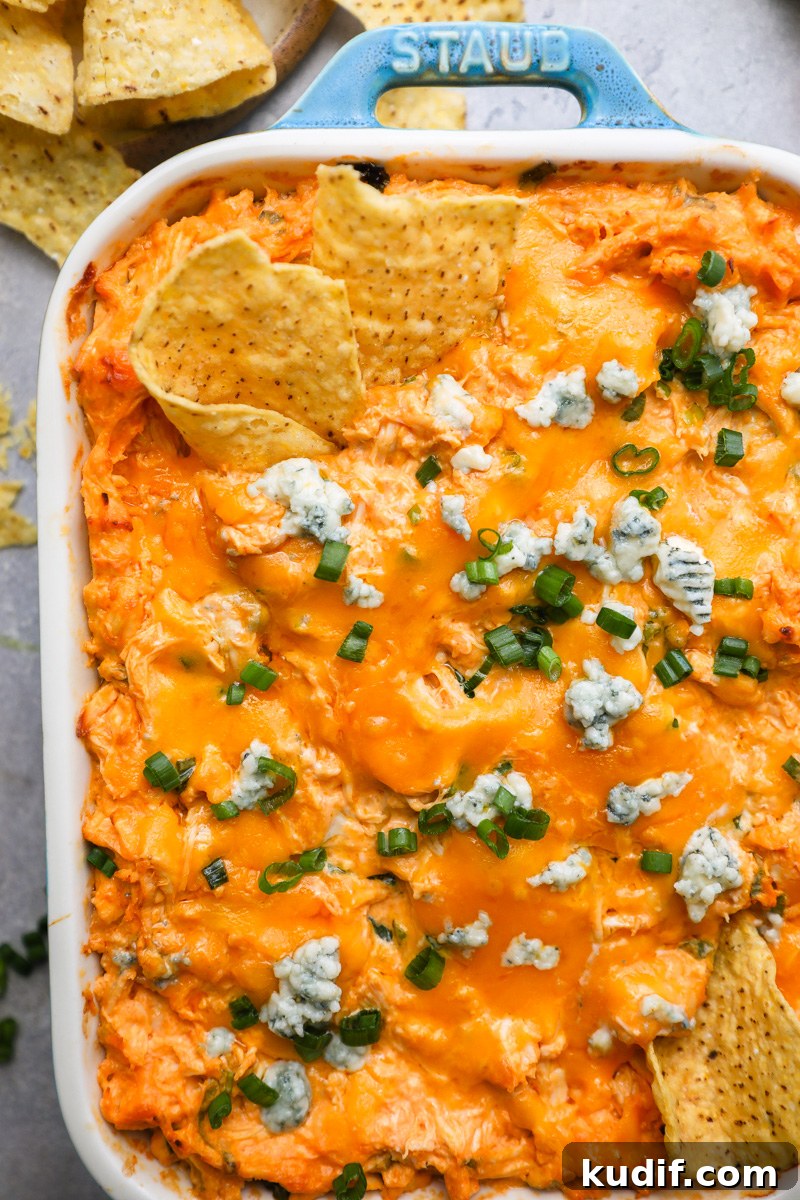 Lightened-Up Buffalo Chicken Dip Recipe for Game Day 6 A close up photo of baked buffalo chicken dip in a casserole dish with tortilla chips digging into it