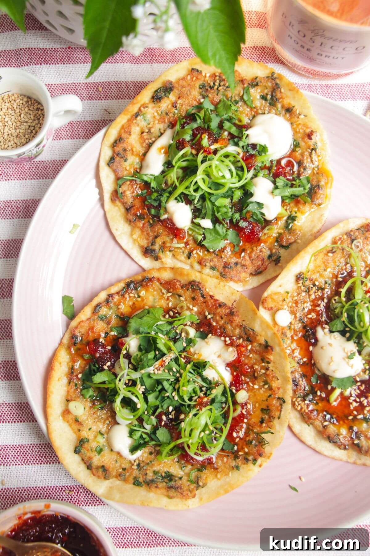 Smash Shrimp Toast Tacos — Crispy Prawn Toast Taco Recipe 2 Three prawn toast tacos topped with herbs and aioli on a pink plate.